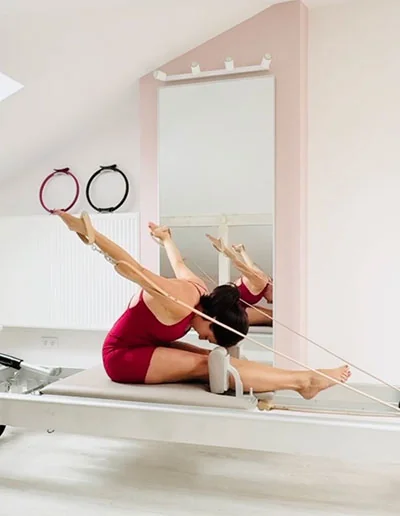 Ćwiczenie w siadzie z paskami na reformerze w studiu Pilates